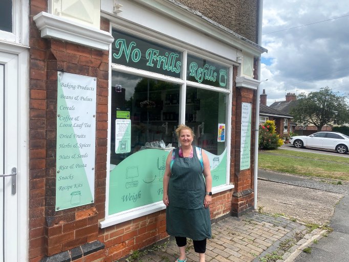 Fran Barney dressed in a green apron stands outside of her shop, No Frills Refills, in Ibstock