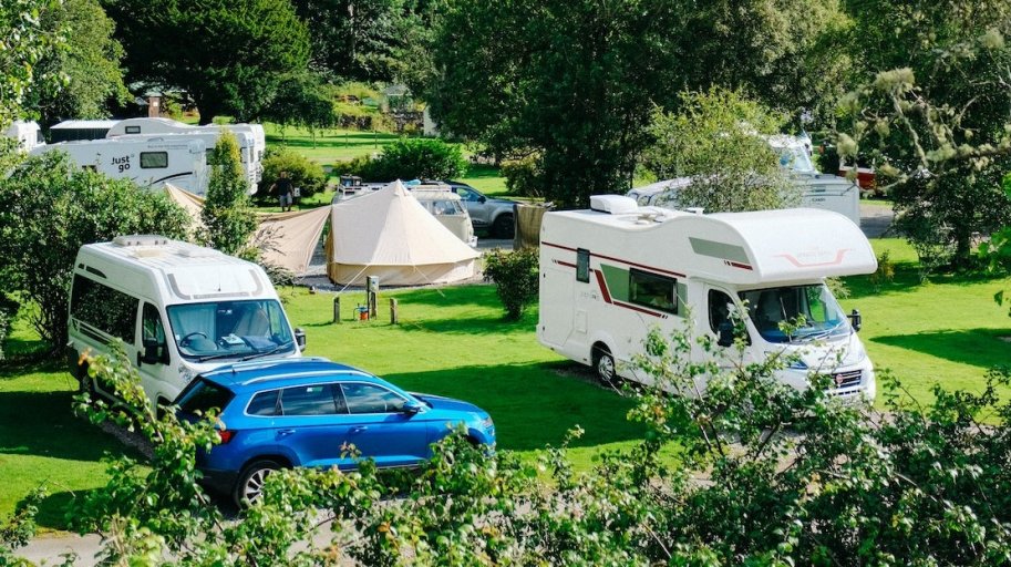 Campervans and bell tent in a large green camping field