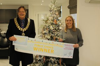 Picture of a man (Chairman Cllr Ray Morris) and a woman (shop owner of Elizabeth Grace Hair), holding a banner declaring the shop as the winner of the public vote for the 2023 Coalville illuminations Award.