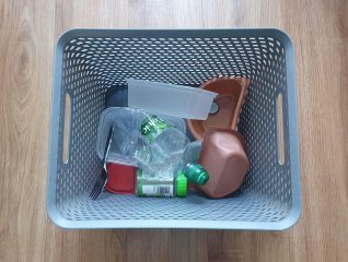 Plastic storage basket with plastic, cans and tins inside.